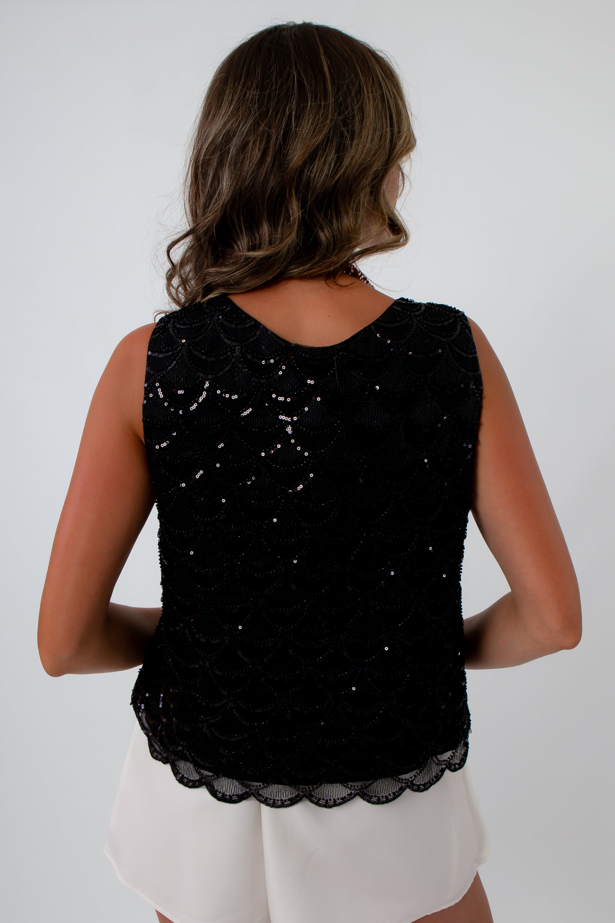 Black sequin top for dinner date, features a scalloped trim and all over sequins