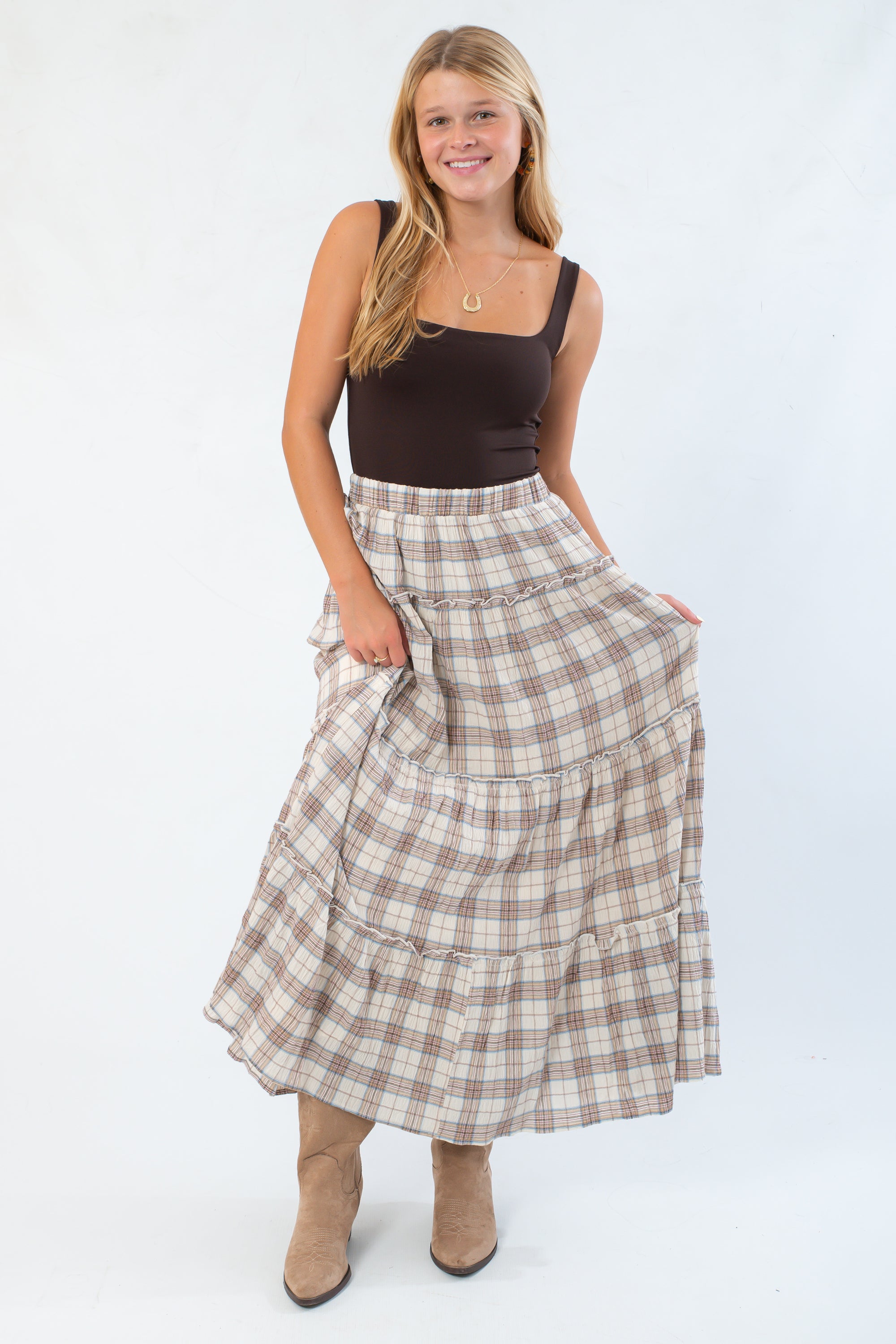 Model wearing basic brown sleeveless bodysuit with scoop neckline, paired with boots and plaid skirt for a cozy fall look.