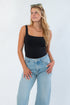 RD Style Scoop Bodysuit Black features a sleek sleeveless design with a scoop neckline, styled with light-wash jeans for a chic layered look.