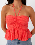 Close-up of coral eyelet halter top with smocked bodice and ruffled hem