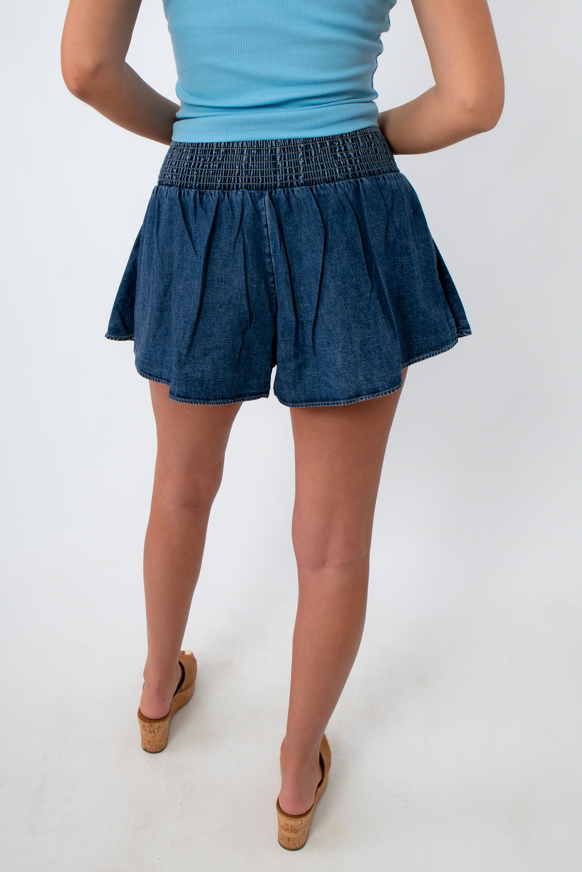 Woman in denim skort with side pocket and tan wedge sandals
