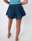 Woman in denim skort with side pocket and tan wedge sandals