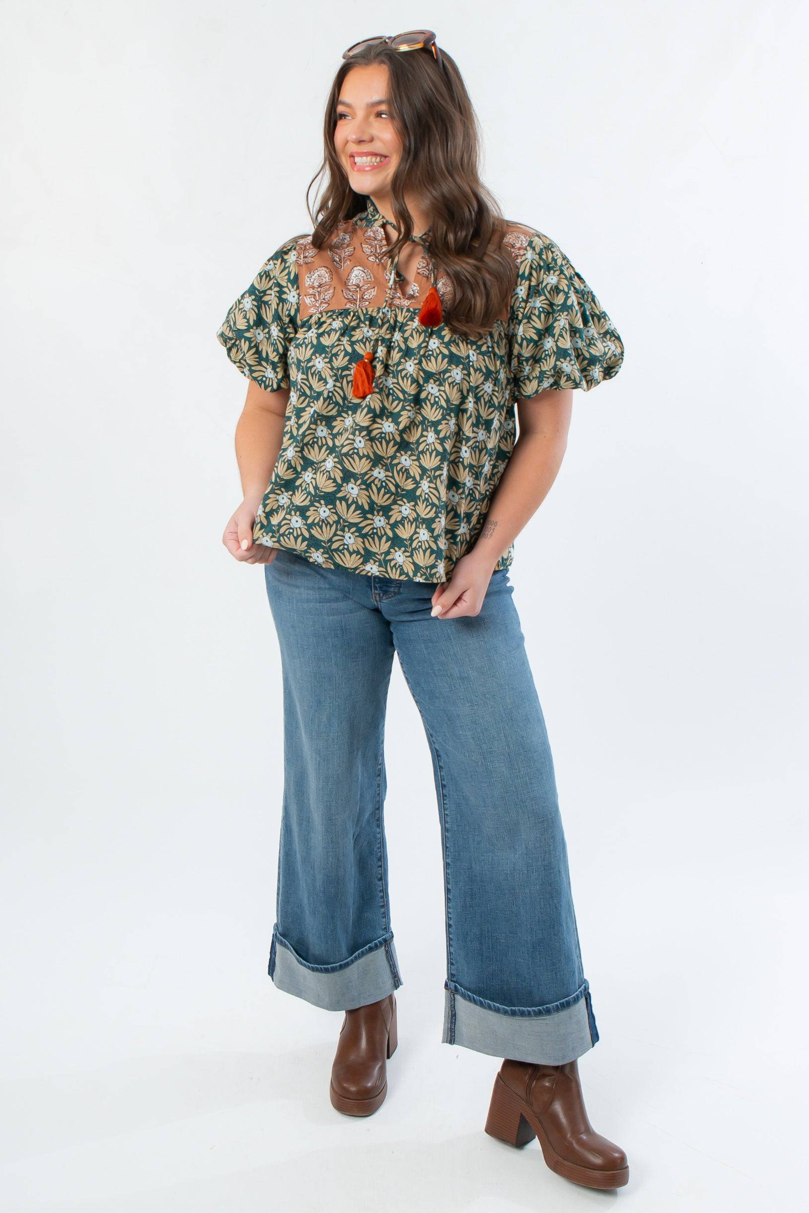 Model wearing THML Green Floral Color Block Puff Sleeve Top paired with wide-leg cuffed jeans and boots, ideal for fall fashion.