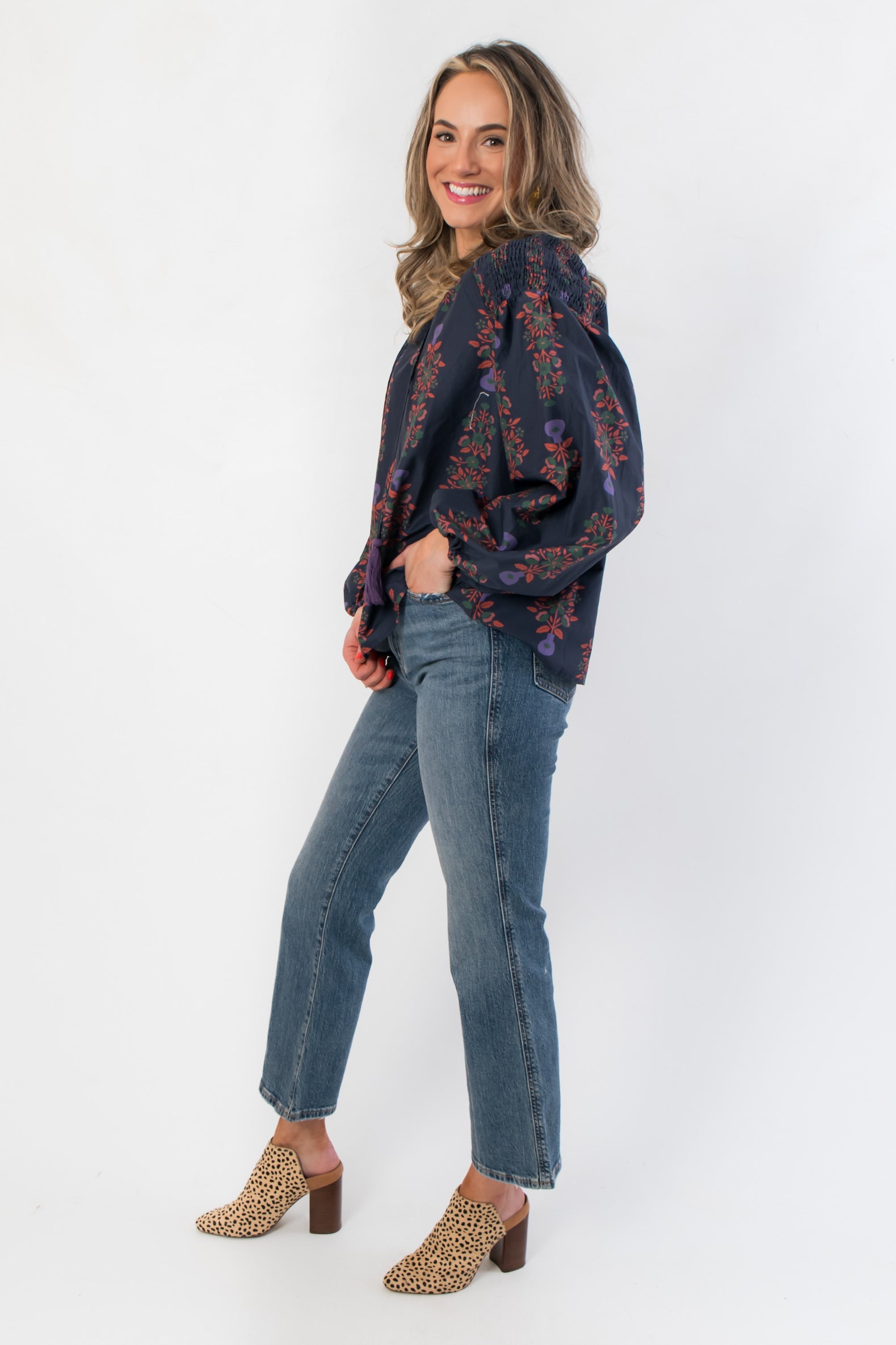 Side view of At Long Last Navy Long Sleeve Blouse showcasing voluminous floral sleeves and relaxed fit, styled with denim and leopard print shoes.