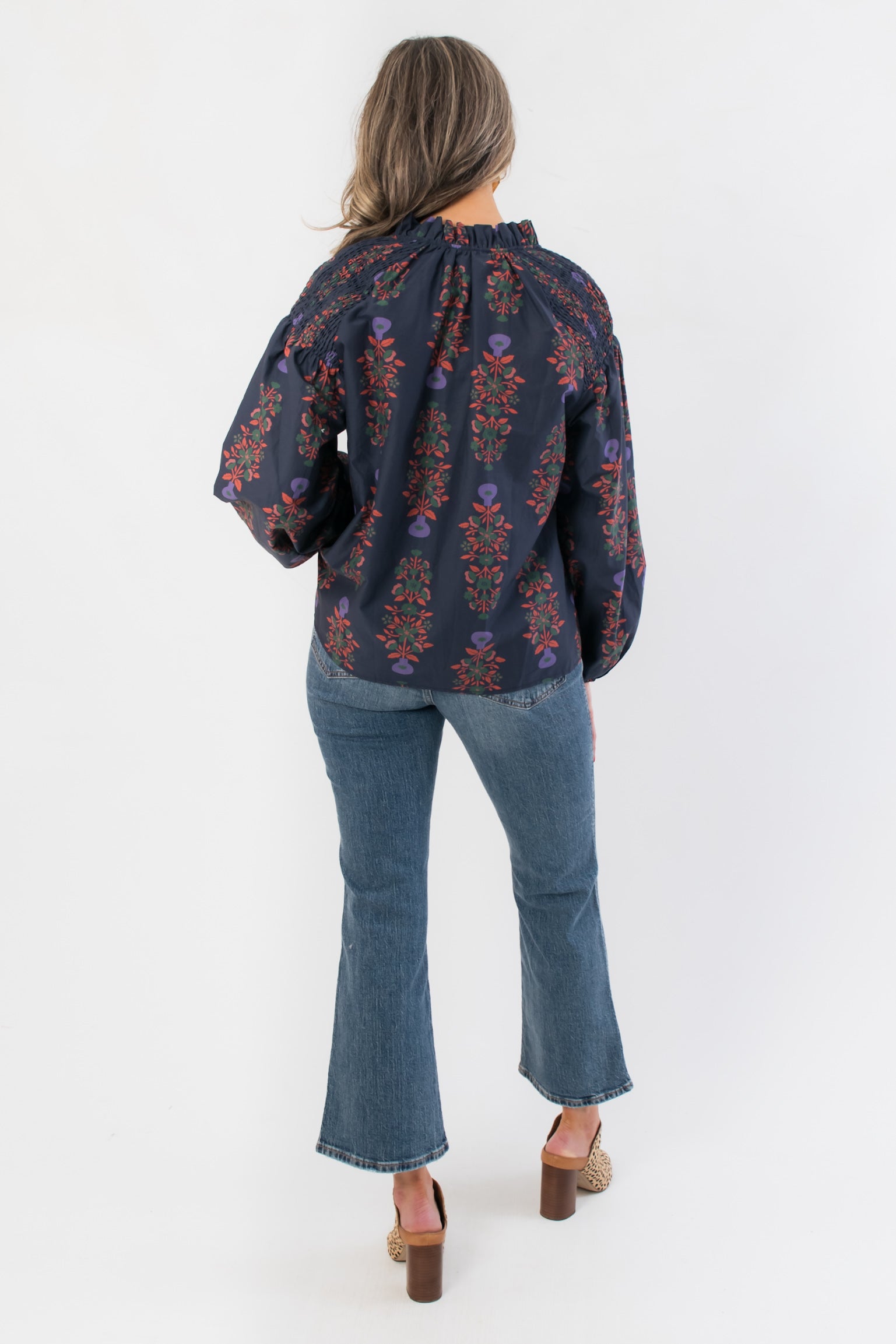 Back view of At Long Last Navy Long Sleeve Blouse highlighting smocked detailing and vintage floral print on navy fabric with balloon sleeves.