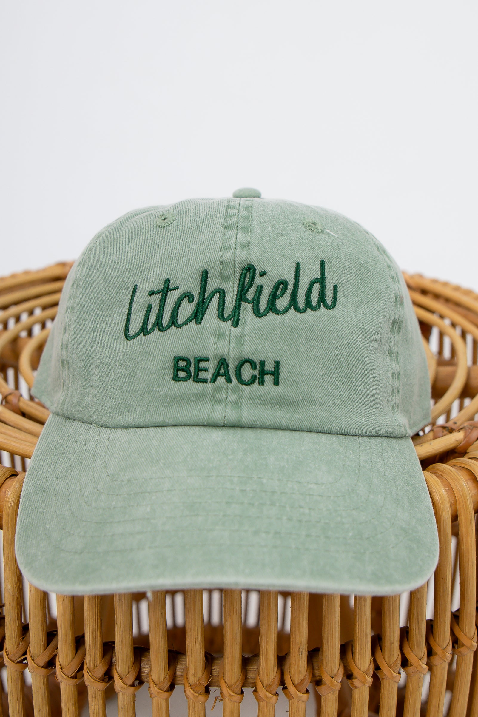 Sunwashed Litchfield Beach embroidered baseball cap on wicker