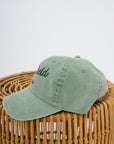 Sage green Litchfield Beach cap displayed on a wicker stand