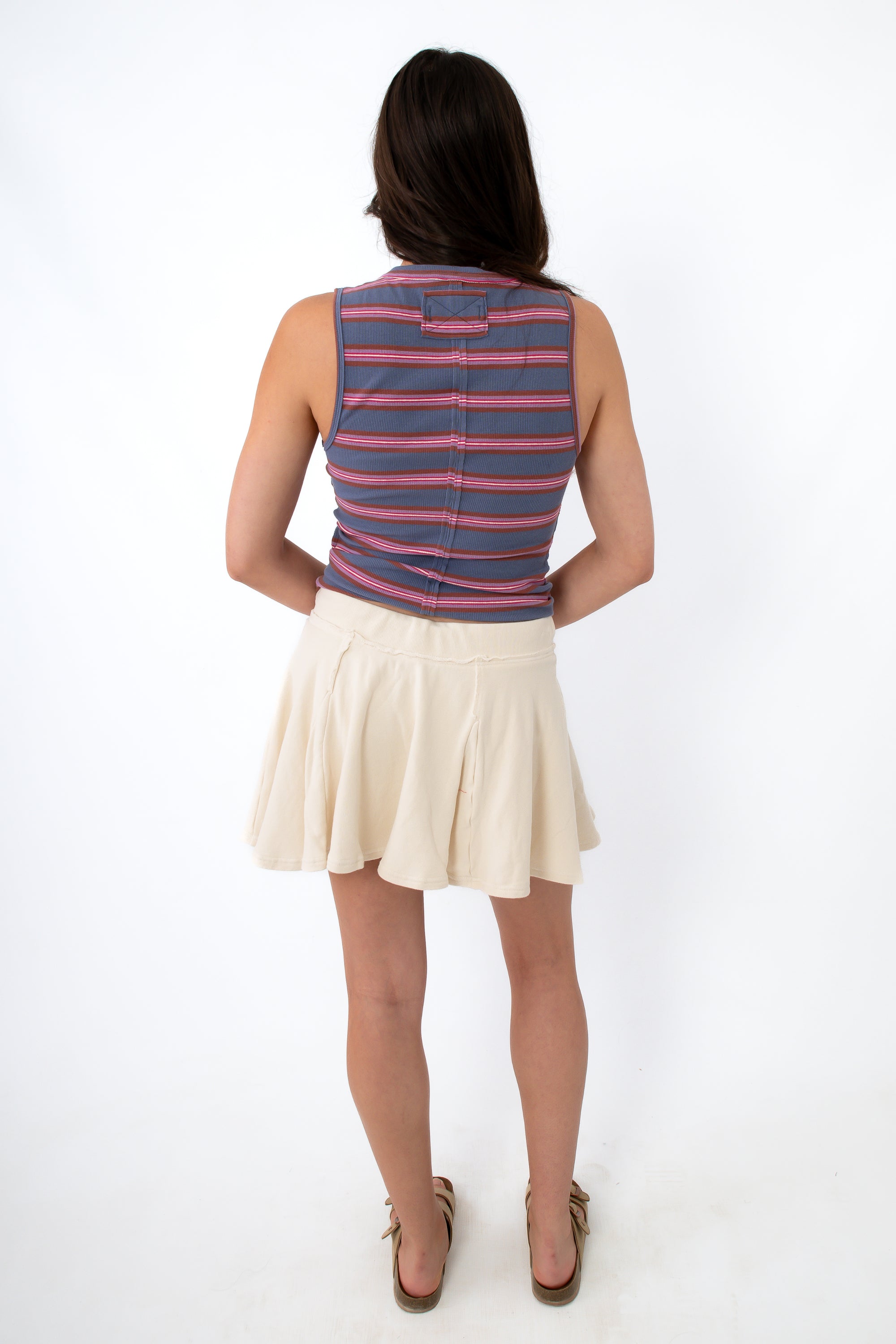 Back view of woman wearing striped sleeveless top and cream skort