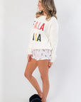 Angled side view of Fa La La White Festive Sweater – Cozy Holiday Knit featuring playful holiday text, ideal for casual winter wear.