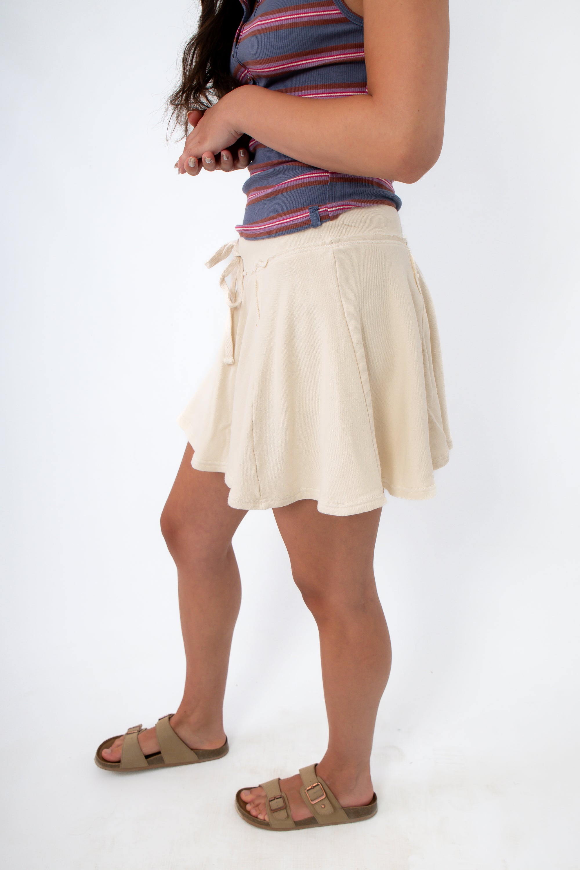 woman in striped tank top and beige skort, side view
