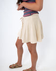 woman in striped tank top and beige skort, side view