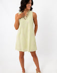 Woman in yellow embroidered sundress with shell necklace, side view