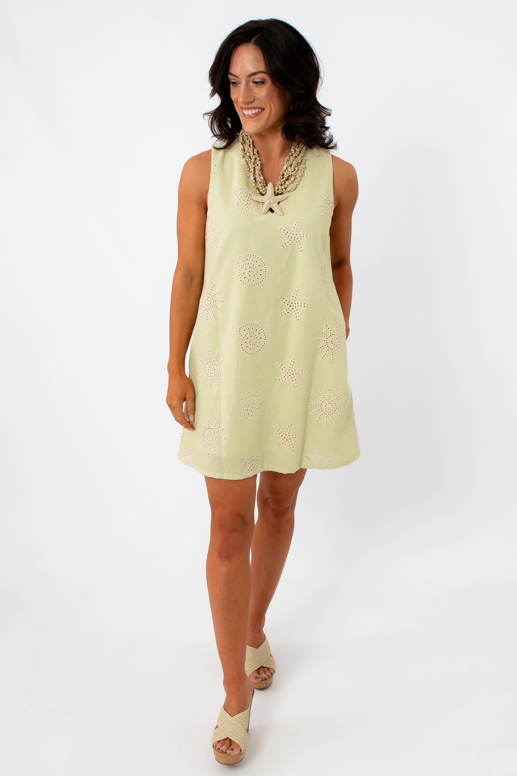 Woman in yellow embroidered sundress with shell necklace, front view