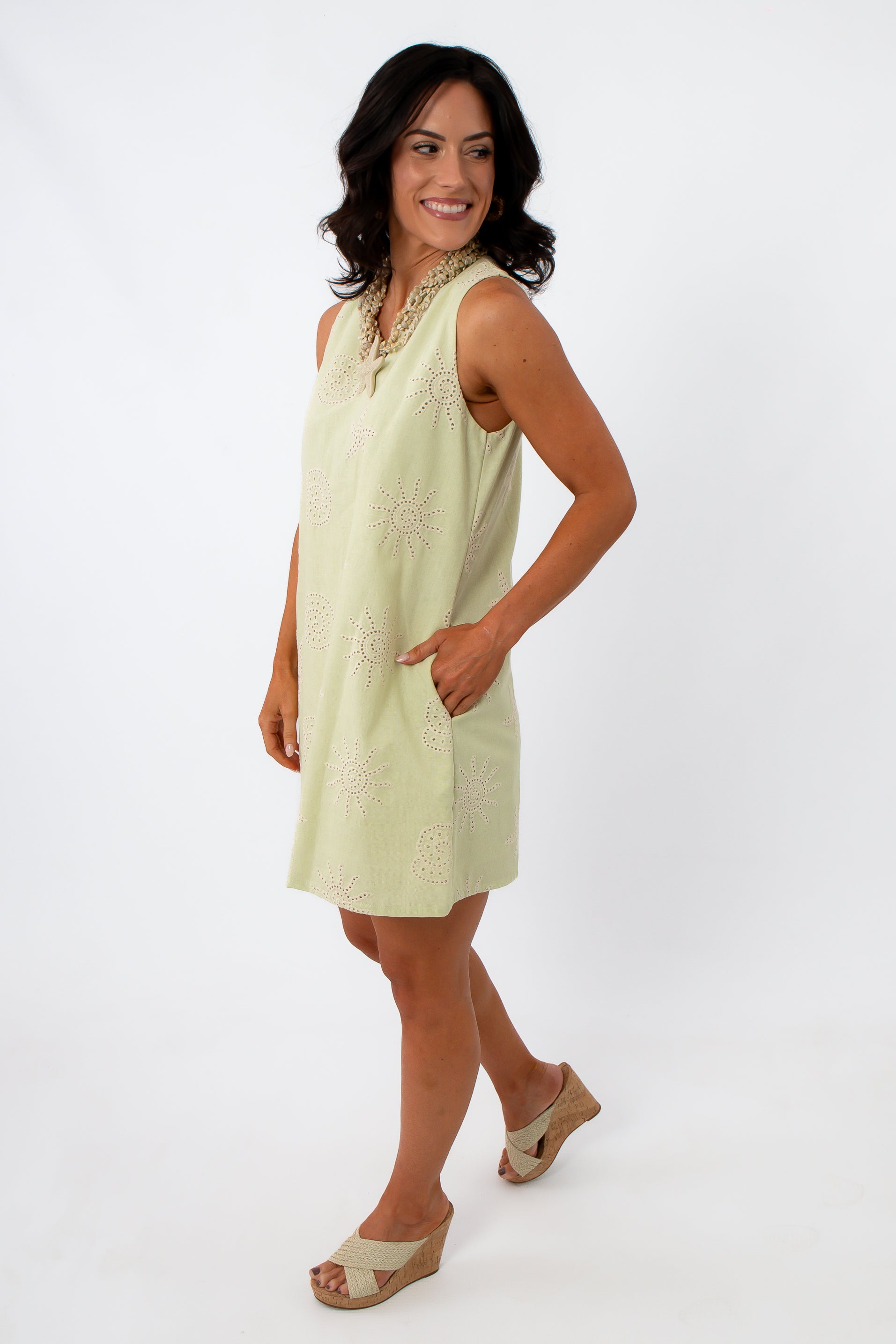 Back view of woman in yellow embroidered sundress with shell necklace