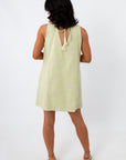 Woman in yellow embroidered sundress with shell necklace, side pose
