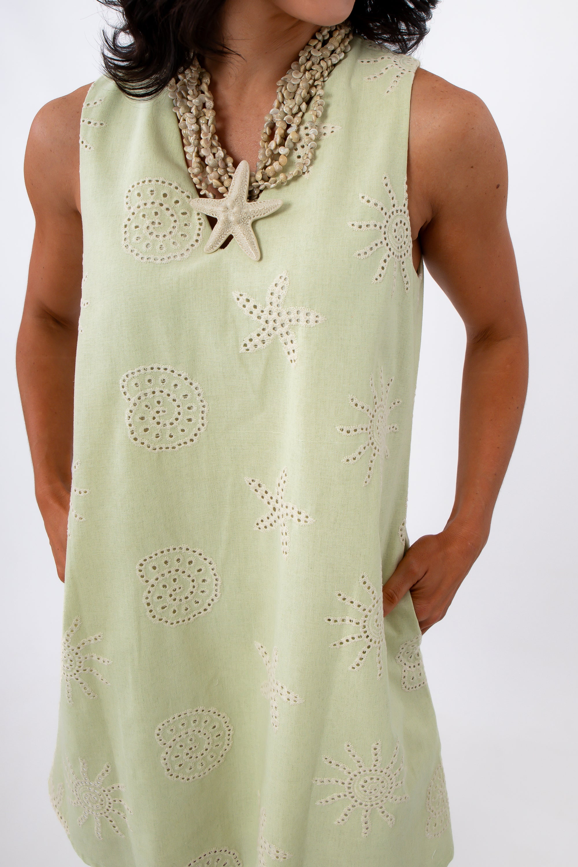Close-up of woman in yellow embroidered sundress with shell necklace