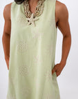 Close-up of woman in yellow embroidered sundress with shell necklace