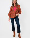 Full view of Carmen Rust Floral Embroidered Blouse – Balloon Sleeve V Neck, paired with cropped jeans and brown boots for fall fashion.