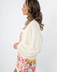 Side view of Clare Cream Waffle Knit Cardigan with floral dress