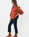 Side profile of Carmen Rust Floral Embroidered Blouse featuring pink floral embroidery and voluminous sleeves, styled with denim and boots.