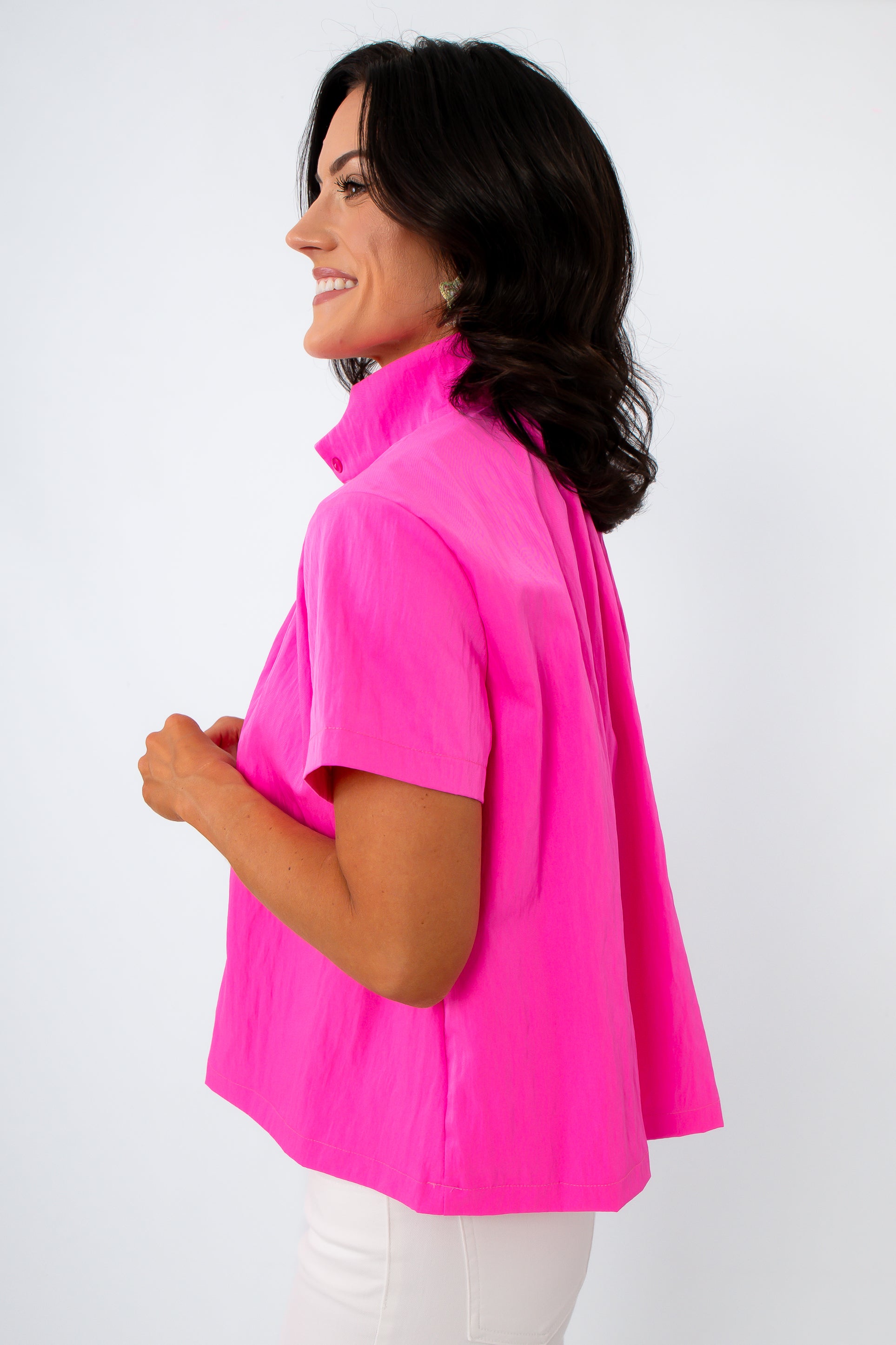 Back view of woman in hot pink blouse with wavy hair and white pants