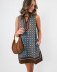 Maureen Chambray Medallion Shift Dress – Floral Sleeveless V Neck featuring side pockets and brown trim, paired with a ruched brown handbag.