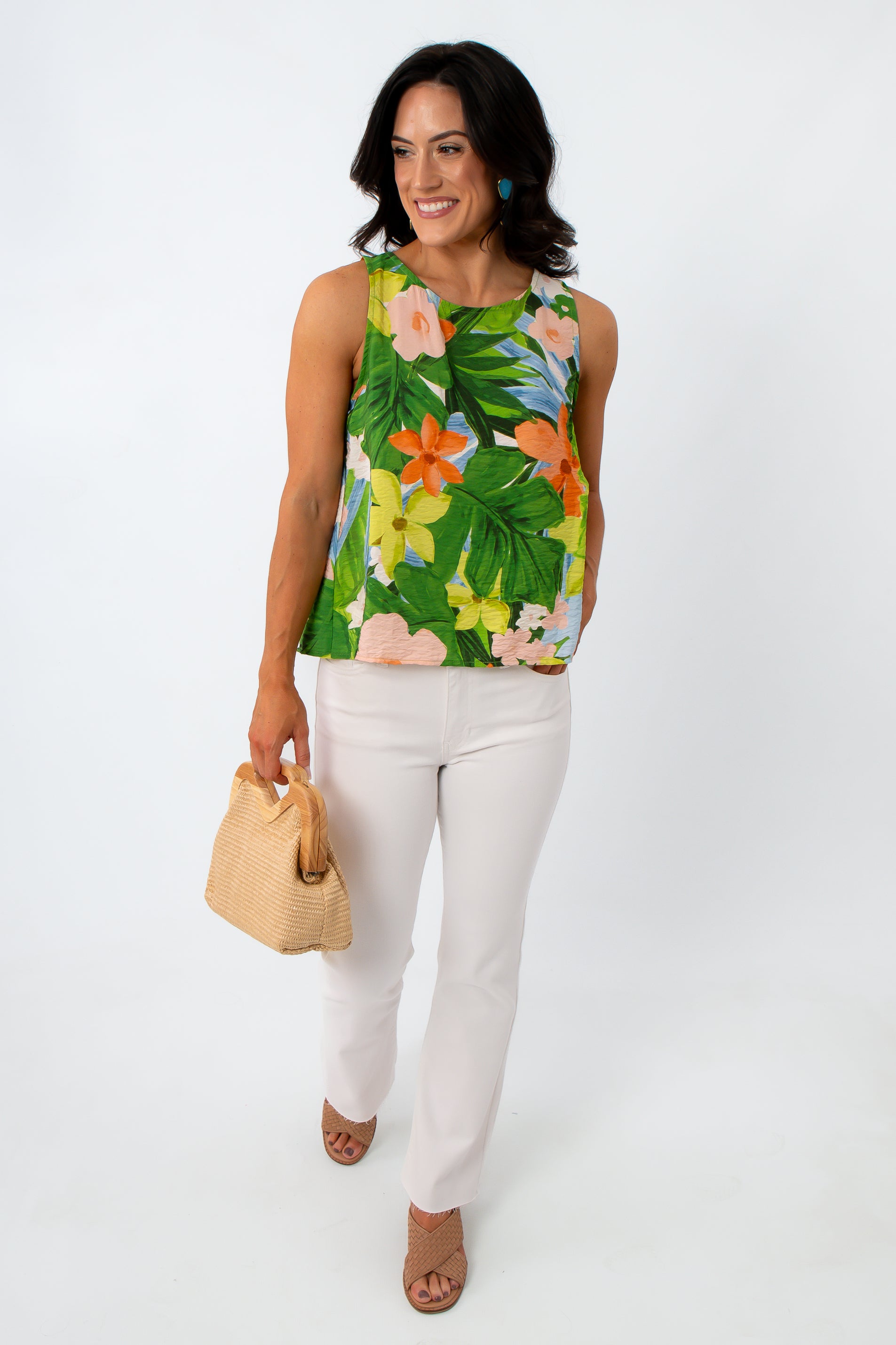 Side view of woman in colorful floral sleeveless blouse, smiling, with dark wavy hair, white background