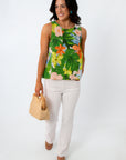 Side view of woman in colorful floral sleeveless blouse, smiling, with dark wavy hair, white background