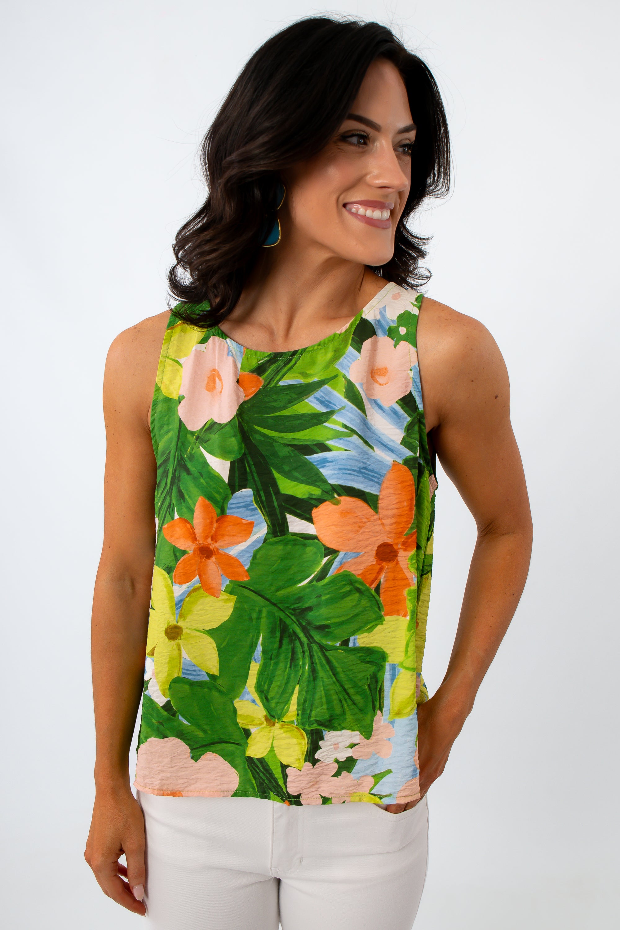 Close-up of woman with dark wavy hair, wearing tropical print sleeveless blouse, smiling, white background