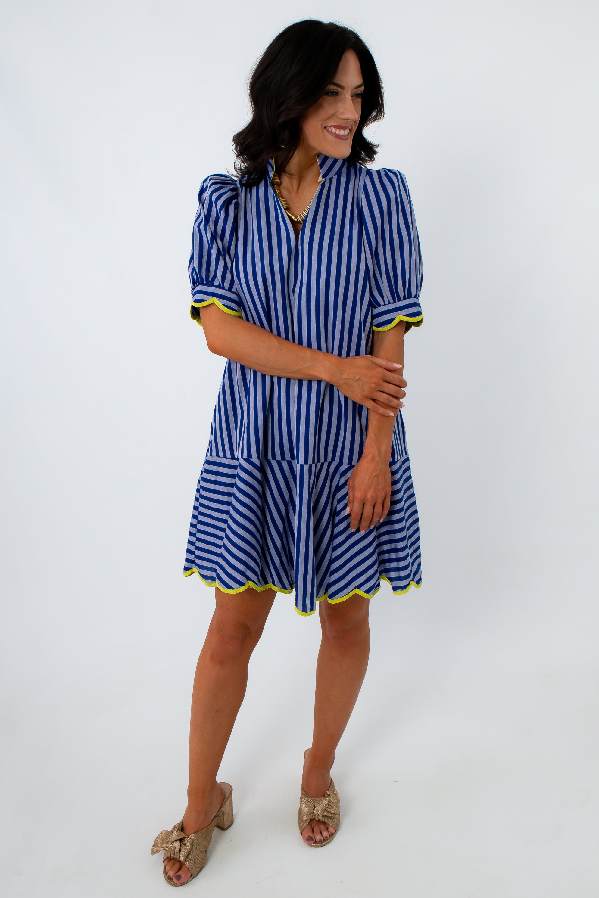 Back view of woman in blue striped dress with yellow trim, showing hairstyle and dress details
