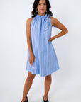 Full-body shot of woman in blue pinstripe dress with ruffled neckline and black heels, smiling