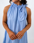 Close-up of woman smiling, showing earrings and dress neckline with bow detail