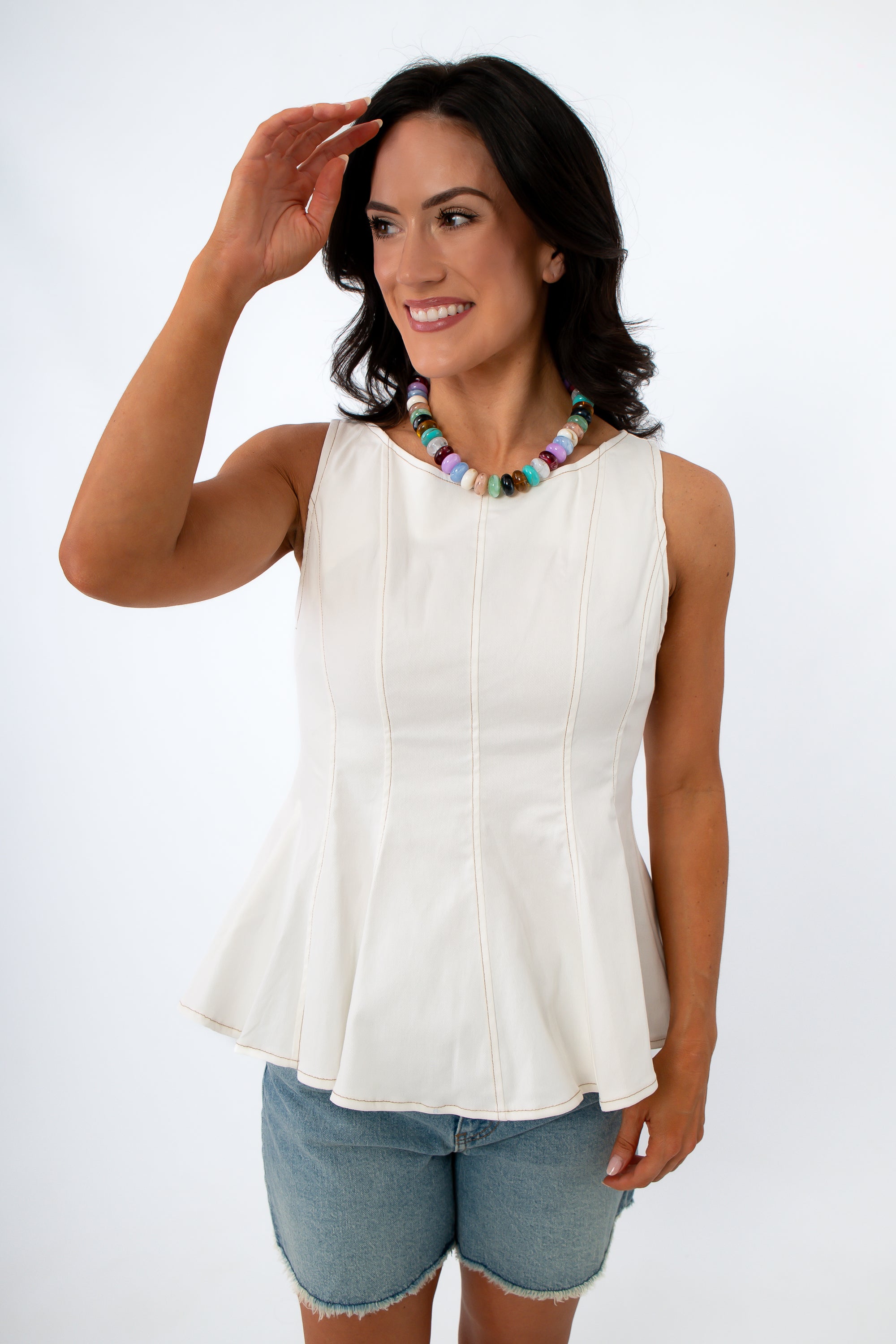 Back view of woman in white sleeveless top with visible zipper, dark hair, smiling
