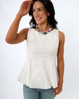 Back view of woman in white sleeveless top with visible zipper, dark hair, smiling