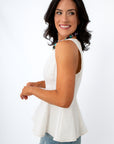 Women wearing white sleeveless peplum top with contrast stitching and a colorful beaded necklace