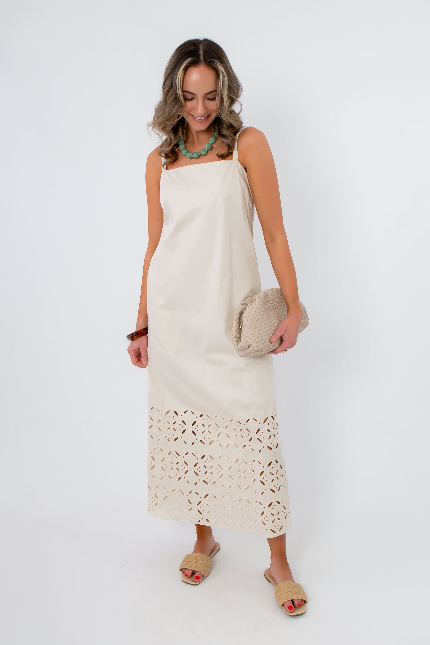 Side view of Seagarden floral eyelet hem midi dress in ecru with model holding clutch