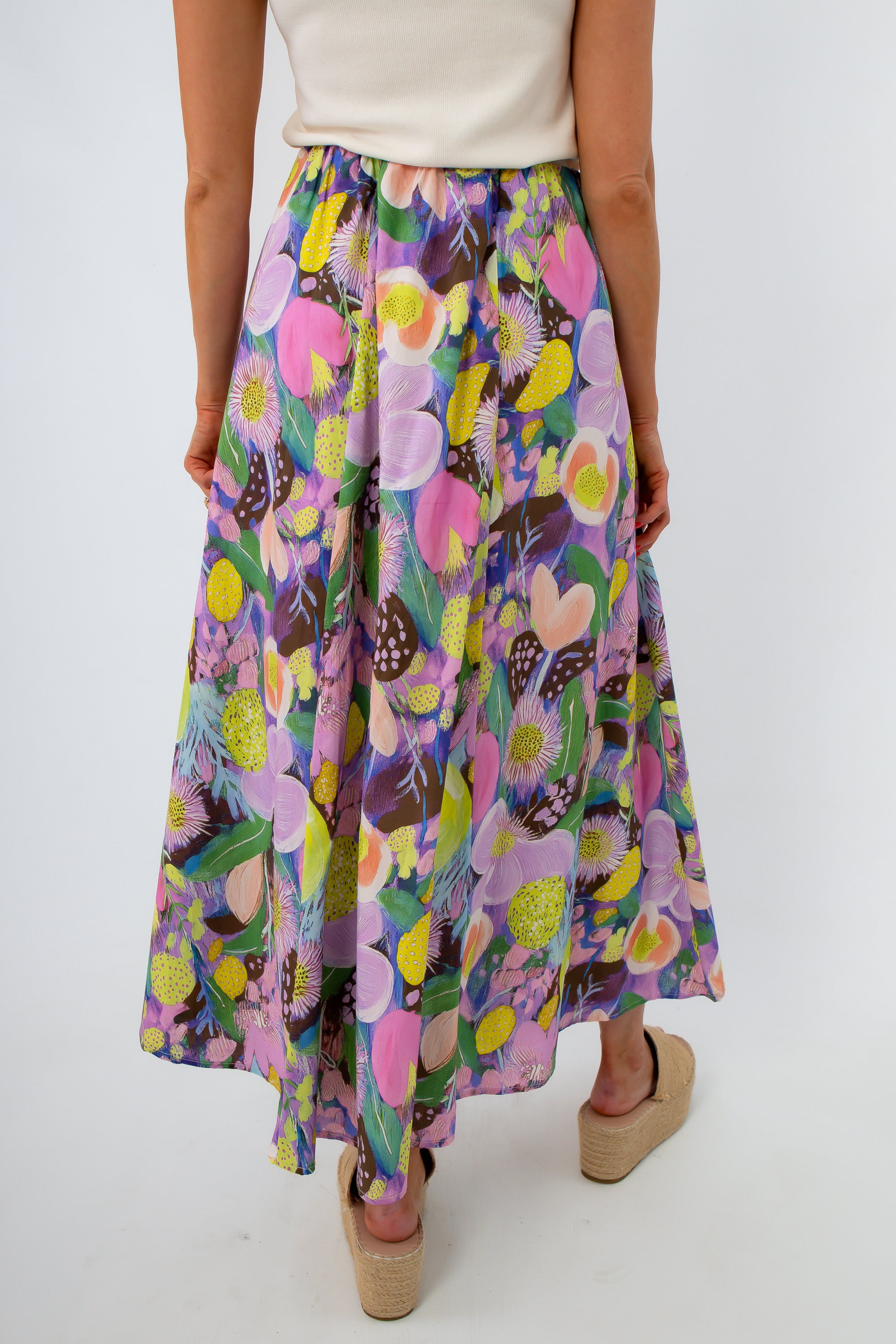 Woman in white top and floral maxi skirt with beige platform sandals