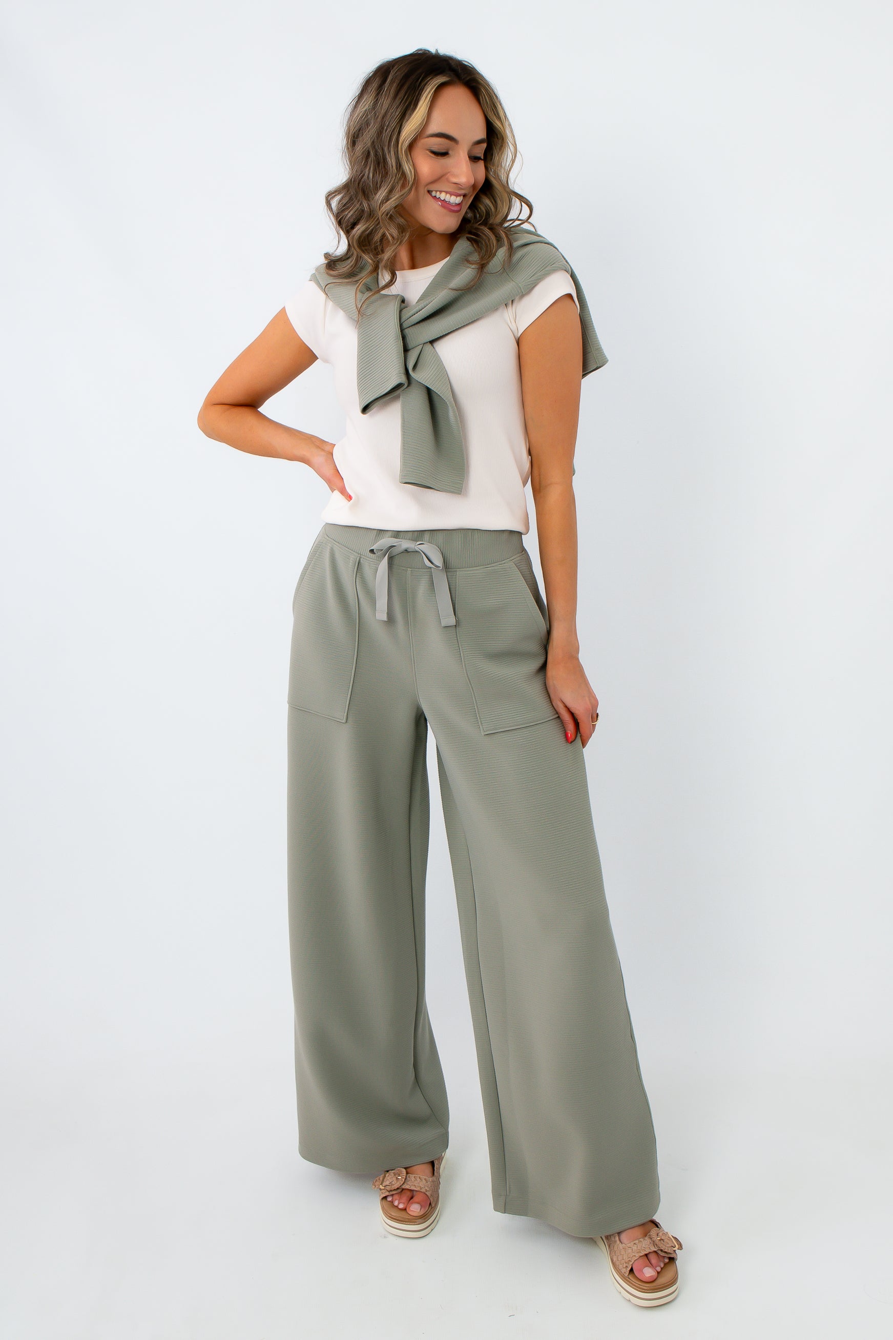 Women wearing sage green wide-leg lounge pants with matching sweatshirt tied around shoulders
