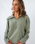 woman wearing sage green zip-up athletic top