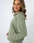 close-up of woman smiling in sage green zip-up top