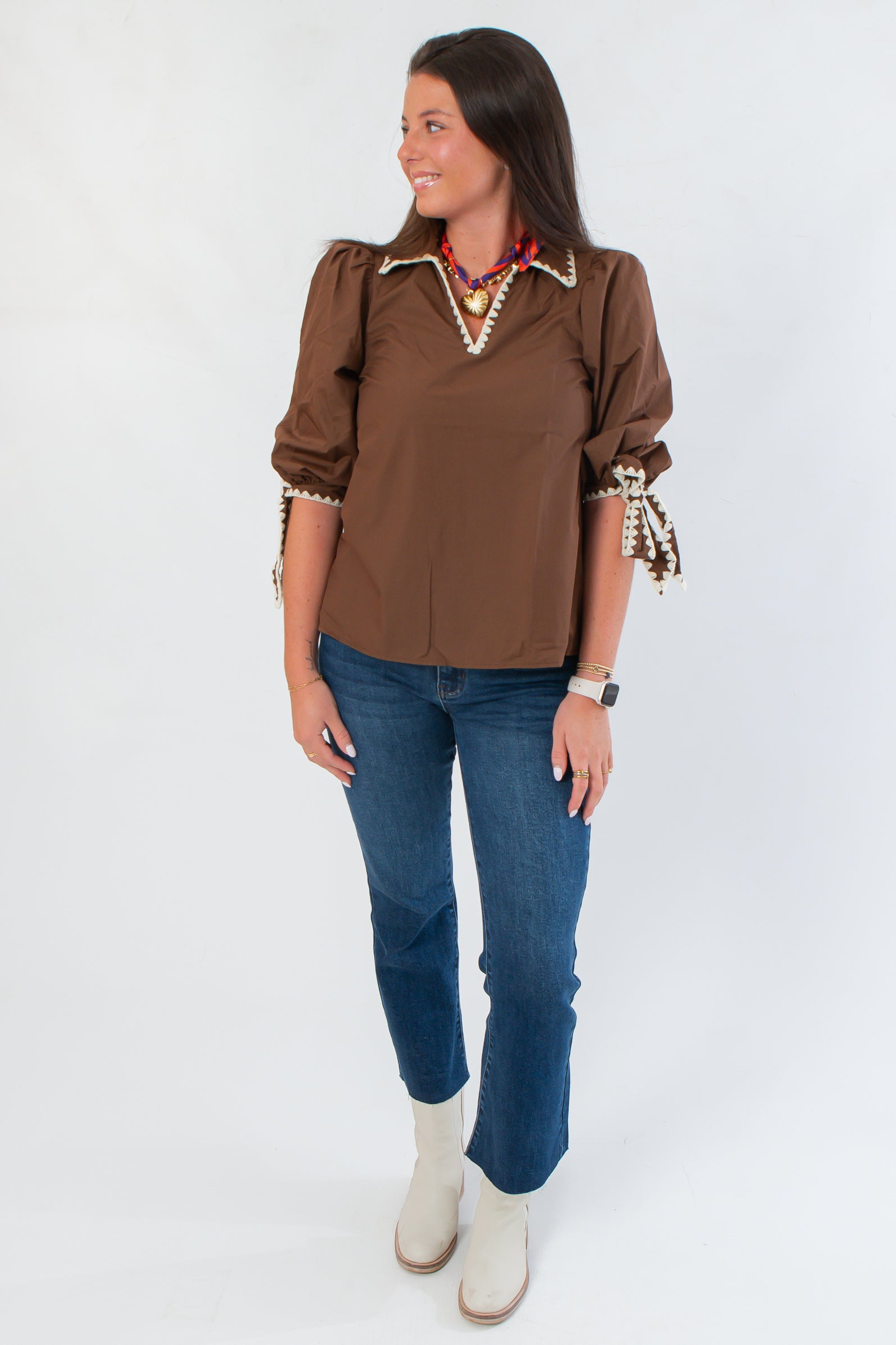 Chic Hazel Brown Whipstitch Collared Blouse with puff sleeves and tie cuffs, paired with jeans for a casual yet polished outfit.