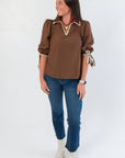 Chic Hazel Brown Whipstitch Collared Blouse with puff sleeves and tie cuffs, paired with jeans for a casual yet polished outfit.