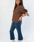 Side view of Hazel Brown Whipstitch Collared Blouse showing puff sleeves and detailed whipstitch trim, styled with denim and boots.