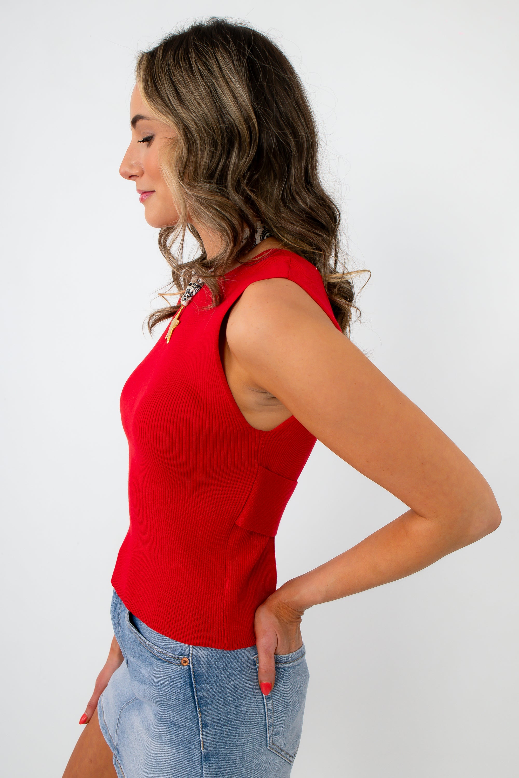Side profile of woman wearing red sleeveless knit top with open back