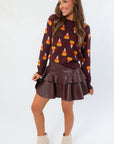 Candy Corn Brown Sweater with festive candy corn print, styled for fall with a flared leather skirt and ankle boots. Ideal for Halloween fashion.