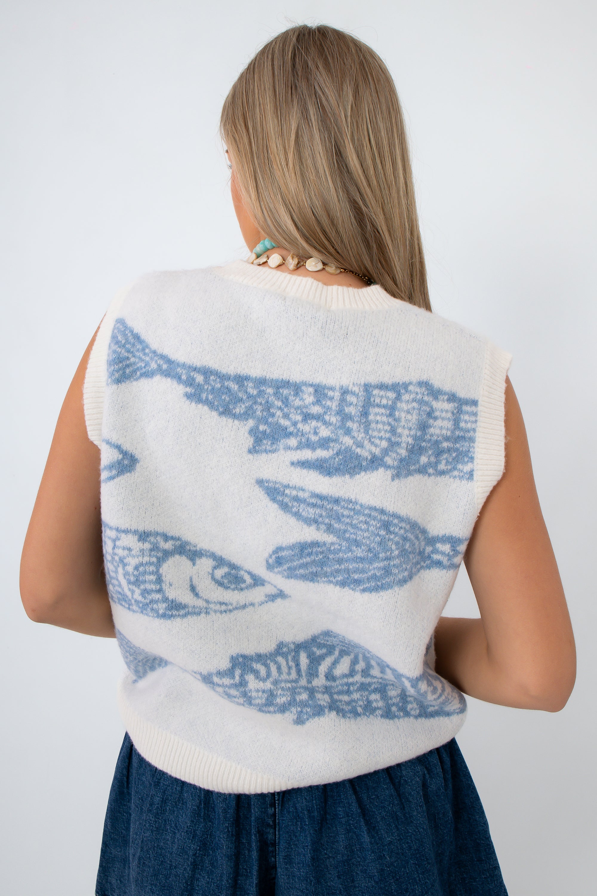 side view of woman in sleeveless knit fish sweater with blue fish pattern