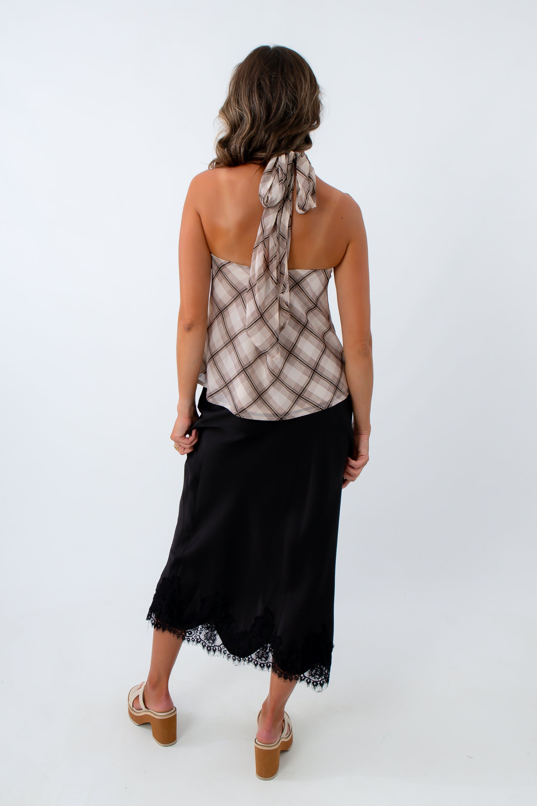 Black satin midi skirt paired with plaid halter top for chic fall outfit, black satin skirt with lace trim