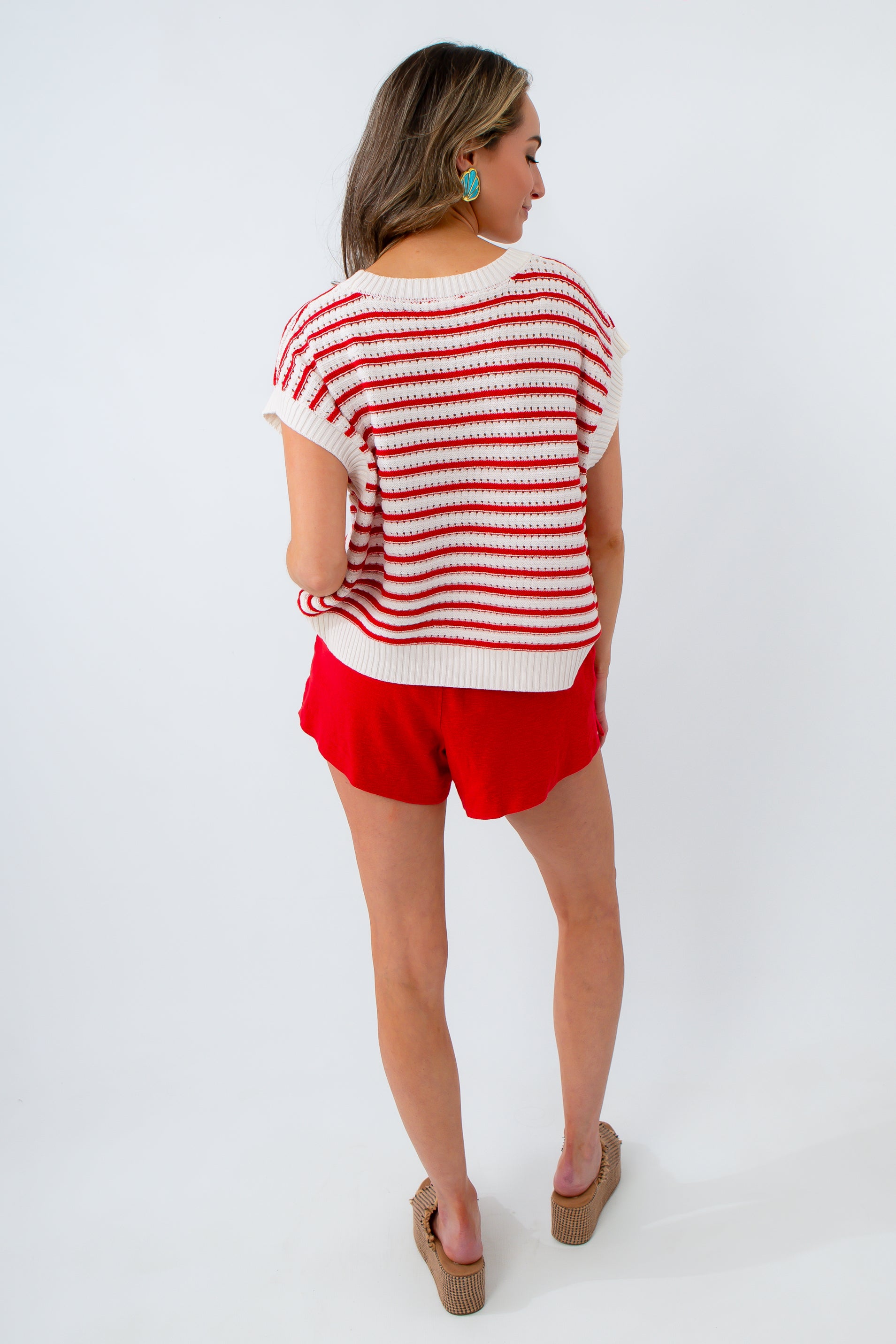 Woman wearing a red and white striped shirt and red shorts on a white background