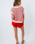 Woman wearing a red and white striped shirt and red shorts on a white background