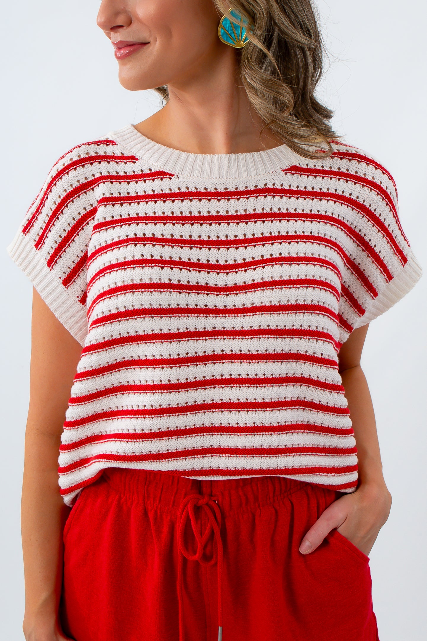 Woman wearing a red and white striped top with red pants on a plain background